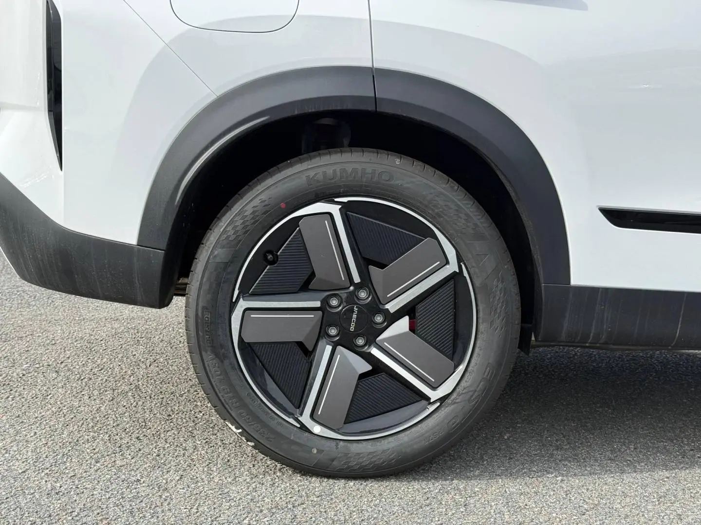 Gros plan sur la roue arrière droite du JAECOO J7 blanc, avec jante alu noire et argentée au design moderne.