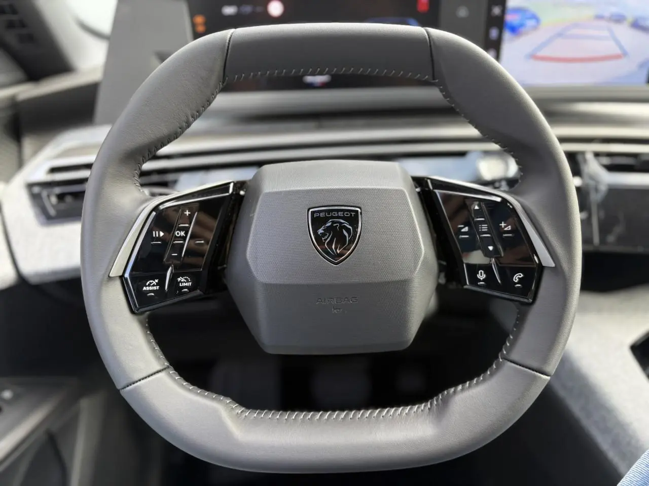Volant compact gris du Peugeot 5008 Hybrid 145 e-DSC6 Allure 2025 avec commandes intégrées noir laqué.