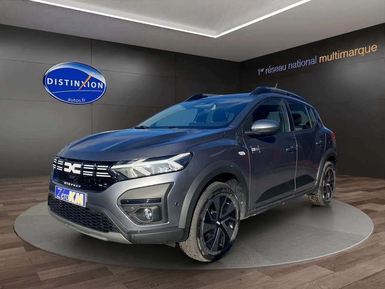 Vue 3/4 avant droite d'une Dacia Sandero Stepway gris schiste avec barres de toit et jantes noires.