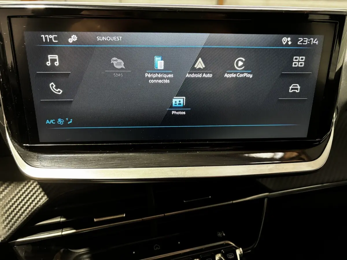 Écran tactile central de 7 pouces du tableau de bord du Peugeot 208 PureTech 100 S&S Active 2024, ambiance intérieure sombre.