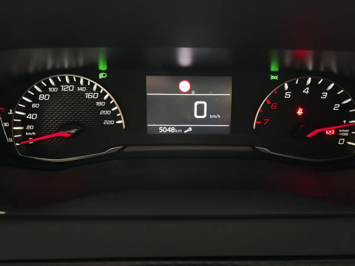 Vue rapprochée du combiné d'instruments numérique de la Peugeot 208 gris clair, affichant 0 km/h et 5048 km au compteur.