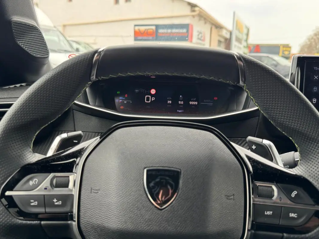 Vue rapprochée du volant Peugeot 208 Hybrid 110 e-DCS6 GT gris avec commandes intégrées et tableau de bord numérique.
