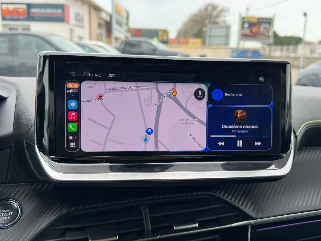 Écran tactile central de la Peugeot 208 gris, affichant navigation et musique, vue intérieure frontale rapprochée.