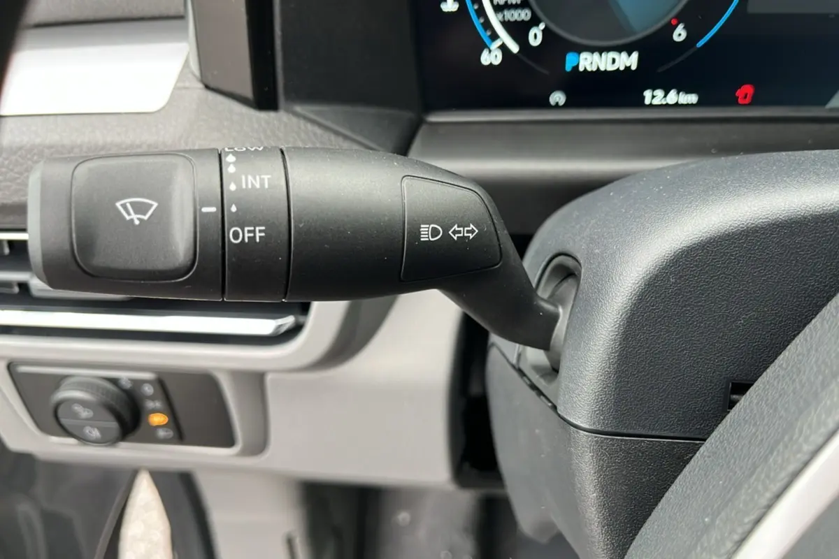 Gros plan sur la manette de clignotant et essuie-glace du Volkswagen Transporter TDI 170 DSG 2026, tableau de bord partiel visible.