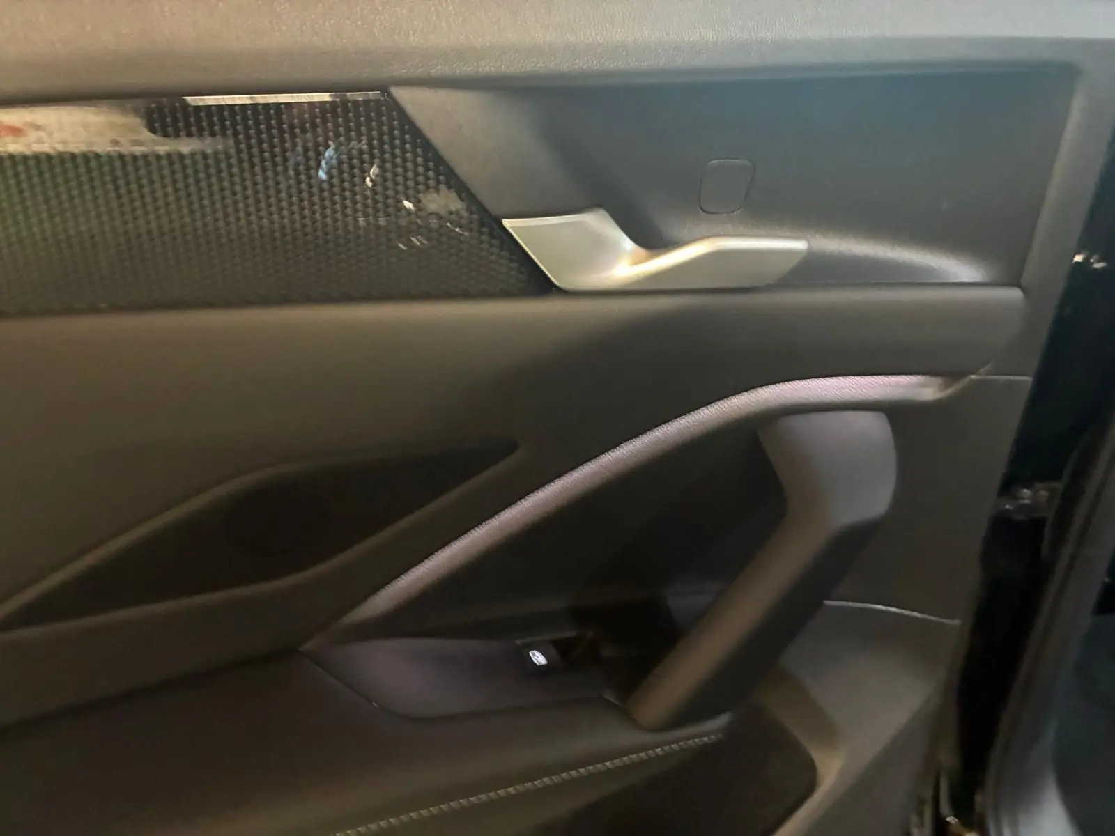 Gros plan sur la porte intérieure côté droit du Volkswagen Tiguan noir avec poignée argentée et insert décoratif noir.