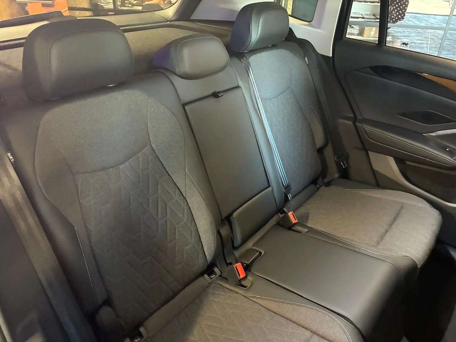 Vue intérieure des sièges arrière du Volkswagen Tiguan 2026, revêtement tissu et cuir noir avec surpiqûres contrastantes.