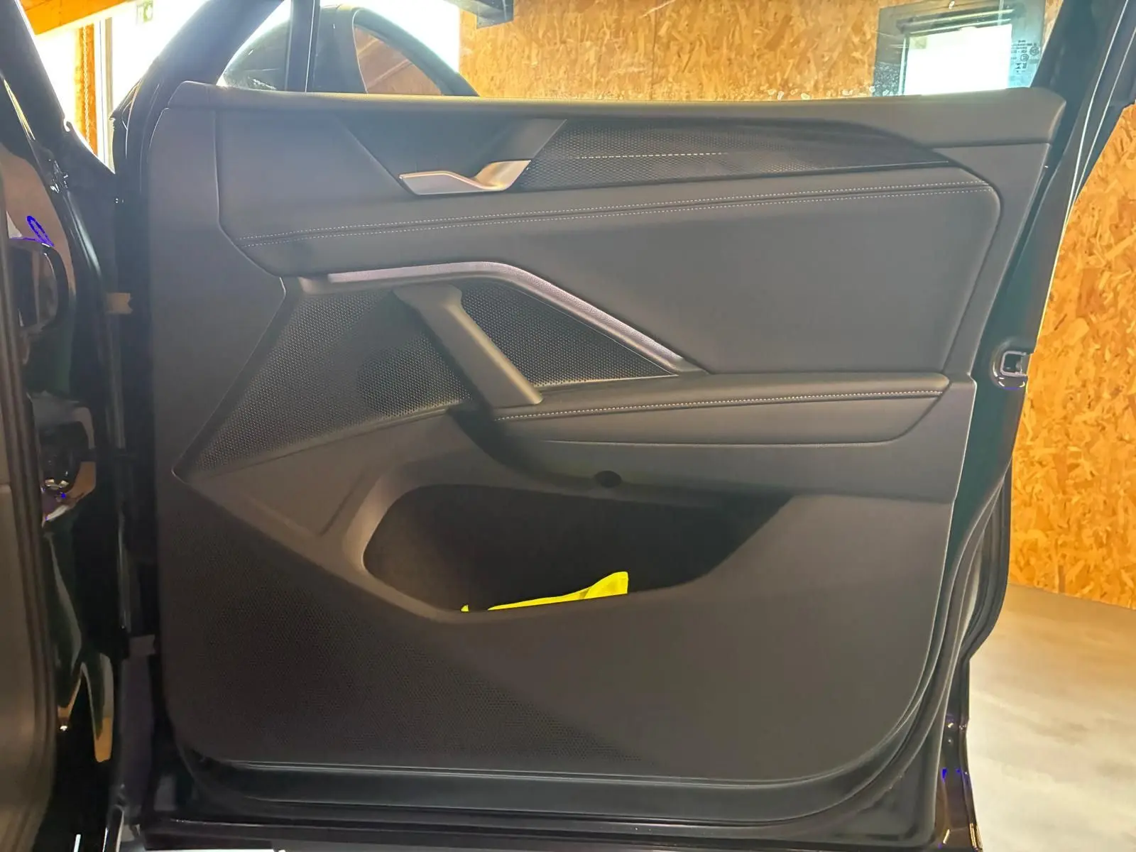 Vue intérieure de la porte avant gauche du Volkswagen Tiguan noir Grenadilla avec garniture en tissu et surpiqûres blanches.