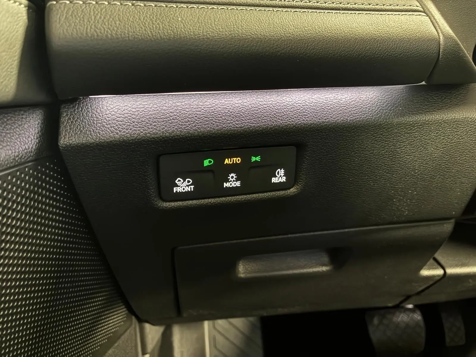 Gros plan sur les commandes d’éclairage automatiques du tableau de bord noir du Volkswagen Tiguan 1.5 TSI 130 DSG Life 30 Years.