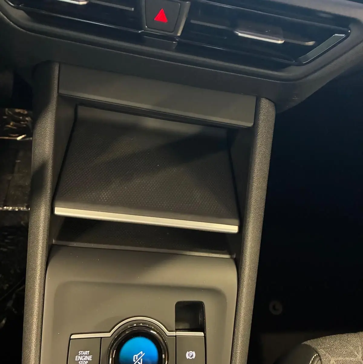 Vue rapprochée de la console centrale noire du Volkswagen Tiguan 2026, avec bouton start/stop et commande électronique frein à main.