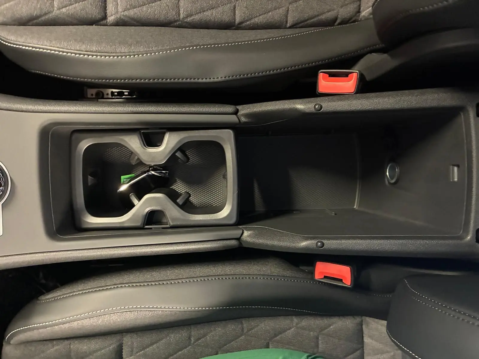 Vue plongeante sur la console centrale noire du Volkswagen Tiguan 2026 avec porte-gobelets et accoudoir en cuir.