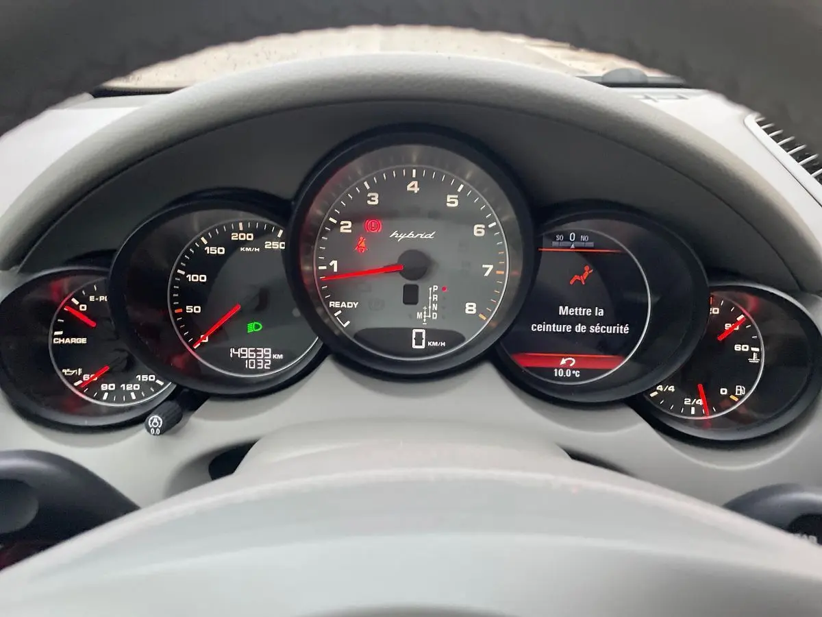 Vue du tableau de bord du Porsche Cayenne S Hybrid 2010 avec compteurs ronds et affichage digital au centre.