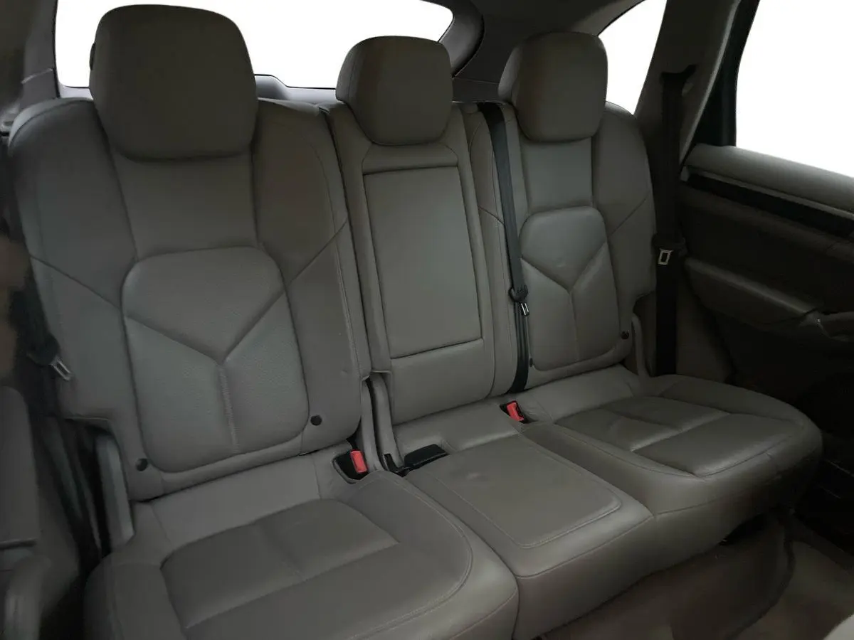 Vue intérieure des sièges arrière en cuir gris du Porsche Cayenne S Hybrid 2010, avec accoudoir central relevé.