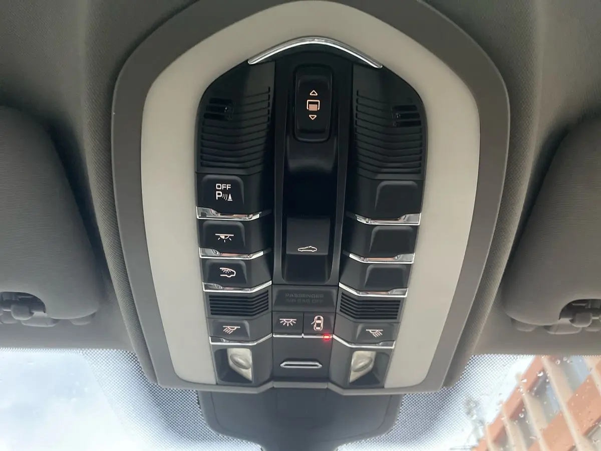 Vue en plongée sur le panneau de commandes au plafond du Porsche Cayenne S Hybrid gris de 2010, avec boutons lumineux.