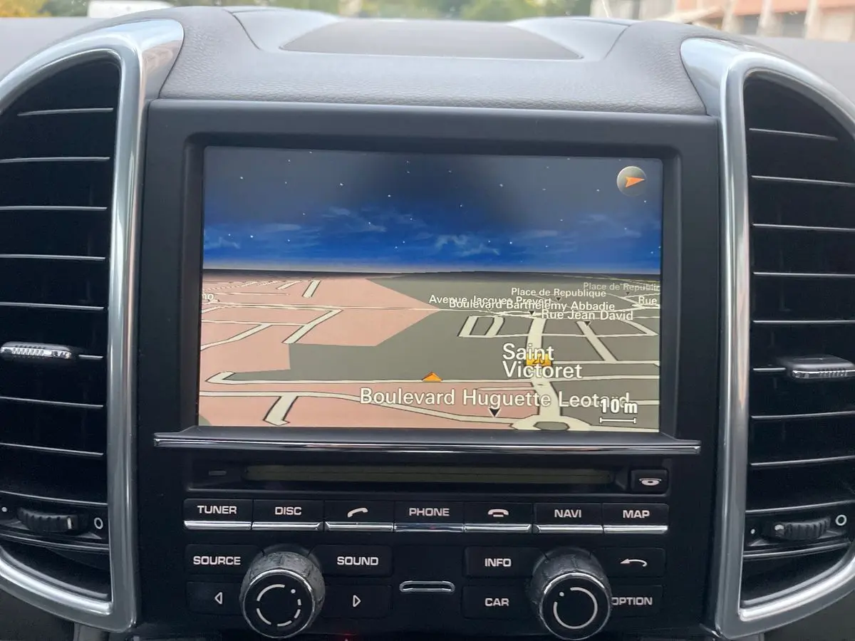 Écran de navigation du tableau de bord d'un Porsche Cayenne S Hybrid gris de 2010, avec commandes intégrées.
