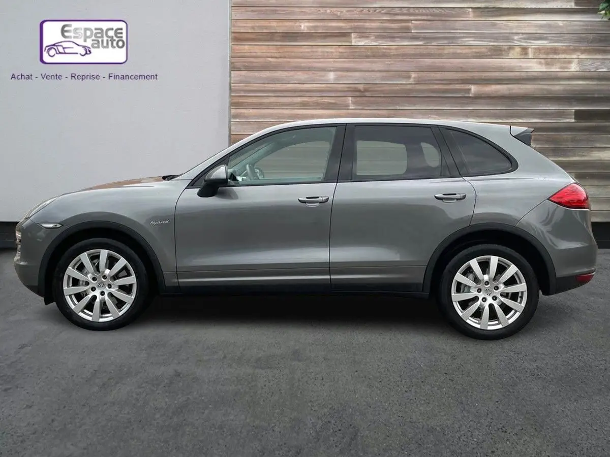 Profil côté gauche d'un Porsche Cayenne S Hybrid gris 2010 avec jantes alliage et badge hybrid visible sur l'aile avant.