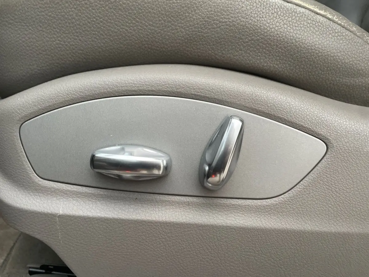 Gros plan sur les commandes de réglage électrique du siège en cuir gris du Porsche Cayenne S Hybrid 2010.