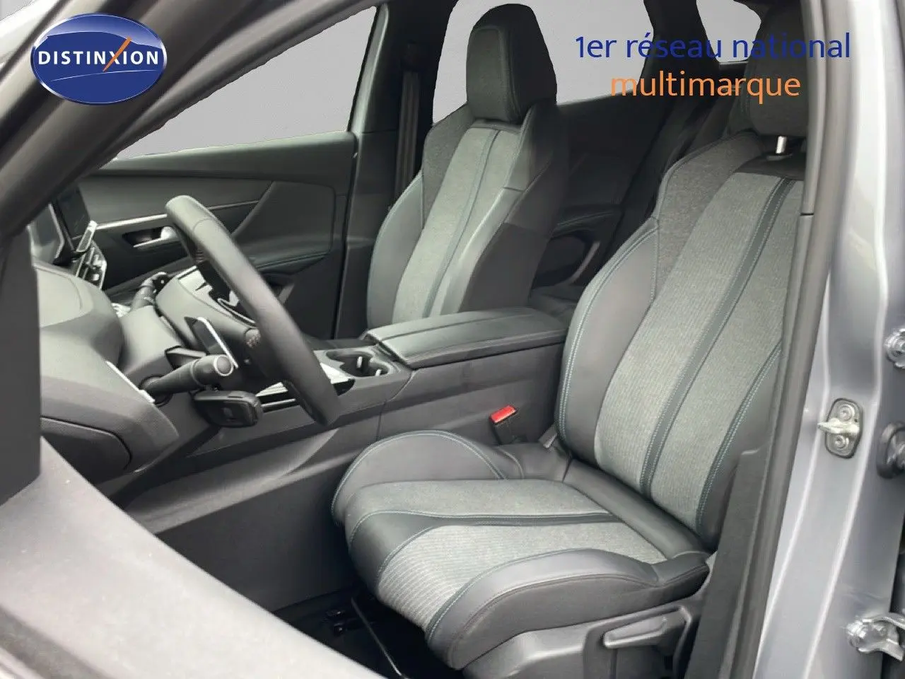 Vue intérieure côté conducteur du Peugeot 3008 gris Artense, sièges tissu et cuir, volant multifonction, console centrale visible.