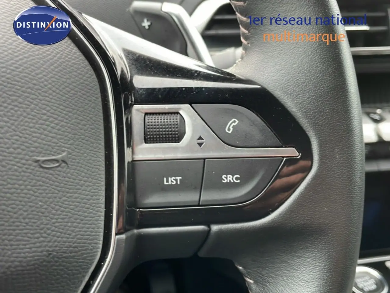 Gros plan sur les commandes gauche du volant cuir noir du Peugeot 3008 gris Artense 2024, boutons LIST et SRC visibles.