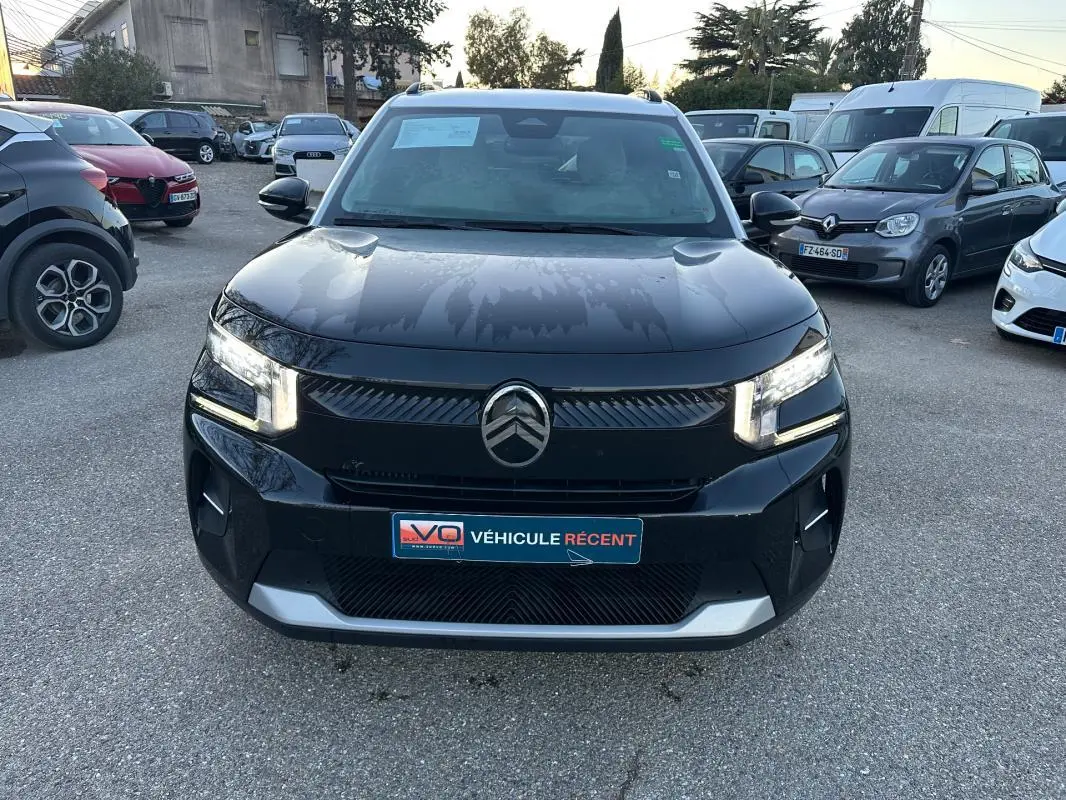 Vue avant d'une Citroën C3 noire 2025 avec phares allumés et calandre au logo chevrons bien visible.