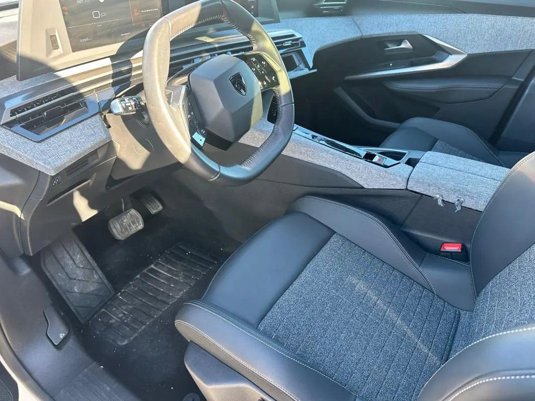 Vue intérieure côté conducteur du Peugeot 3008 Hybrid 145 e-DCS6 Allure 2025, avec sellerie mixte cuir et tissu gris.