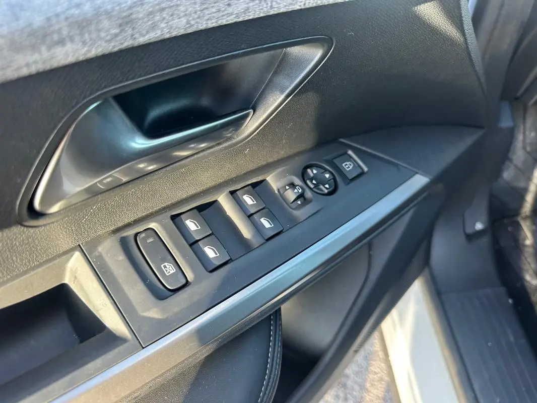 Détail des commandes de lève-vitres et rétroviseurs sur la porte avant gauche d’un Peugeot 3008 blanc 2025.