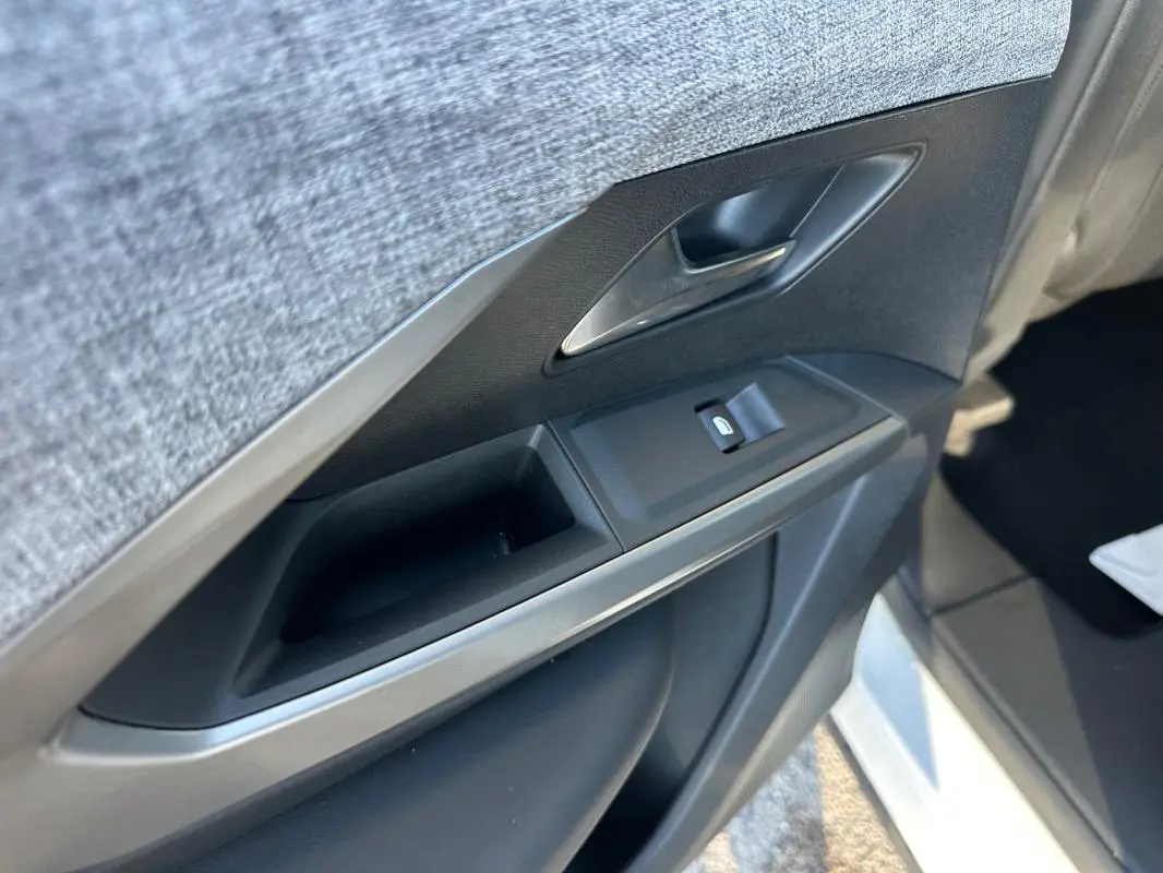 Gros plan sur la porte intérieure côté gauche du Peugeot 3008 blanc, montrant la poignée et la commande de vitre.
