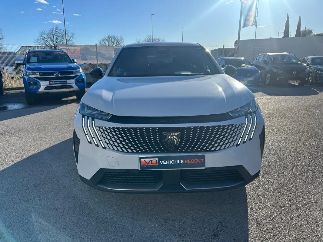 Vue avant d’un Peugeot 3008 Hybrid blanc avec calandre distinctive et feux LED verticaux allumés.