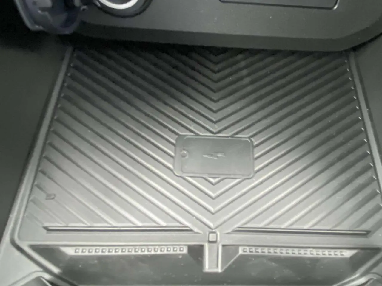 Gros plan sur le tapis de recharge sans fil noir dans l’habitacle du Dacia Duster 1.6 Hybrid 2025.