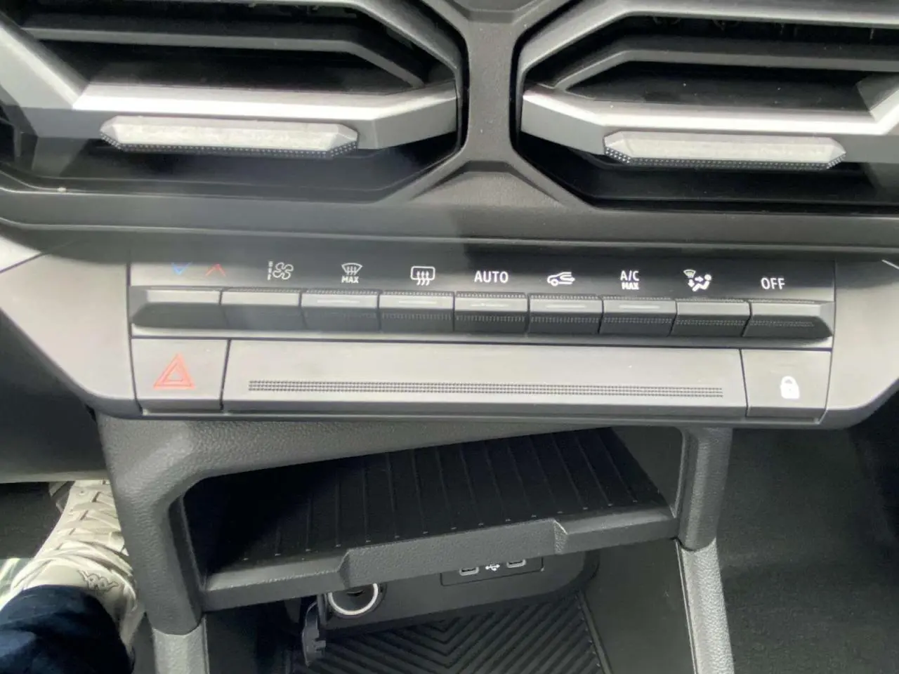 Vue rapprochée de la console centrale du Dacia Duster 2025, avec commandes climatisation et prises USB visibles.