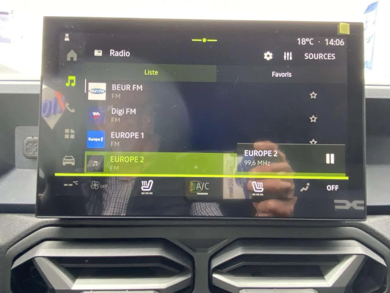Écran tactile central du Dacia Duster 2025 affichant la radio FM avec commandes de climatisation et sièges chauffants visibles.