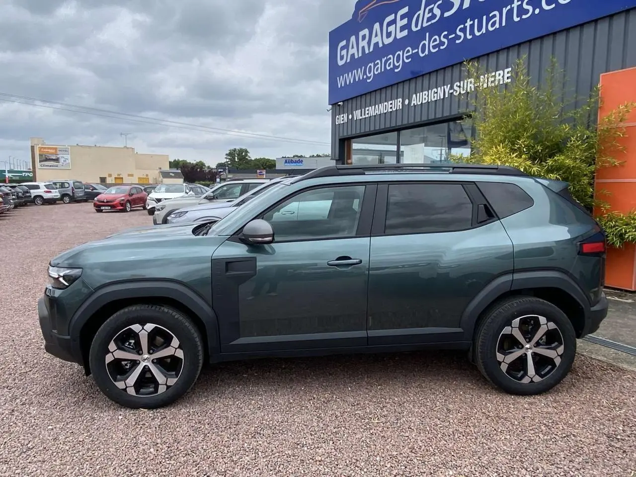 Vue de profil côté gauche du Dacia Duster 1.6 Hybrid 2025 en vert INC avec jantes alliage et détails noirs contrastants.
