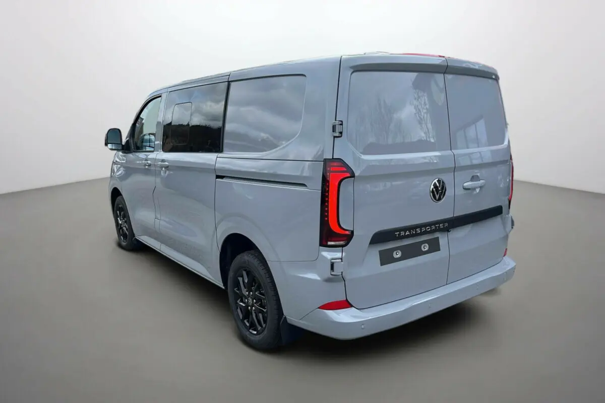 Vue 3/4 arrière droite d’un Volkswagen Transporter TDI 170 DSG ProCab L1 gris Stone avec vitres teintées et jantes alu noires.