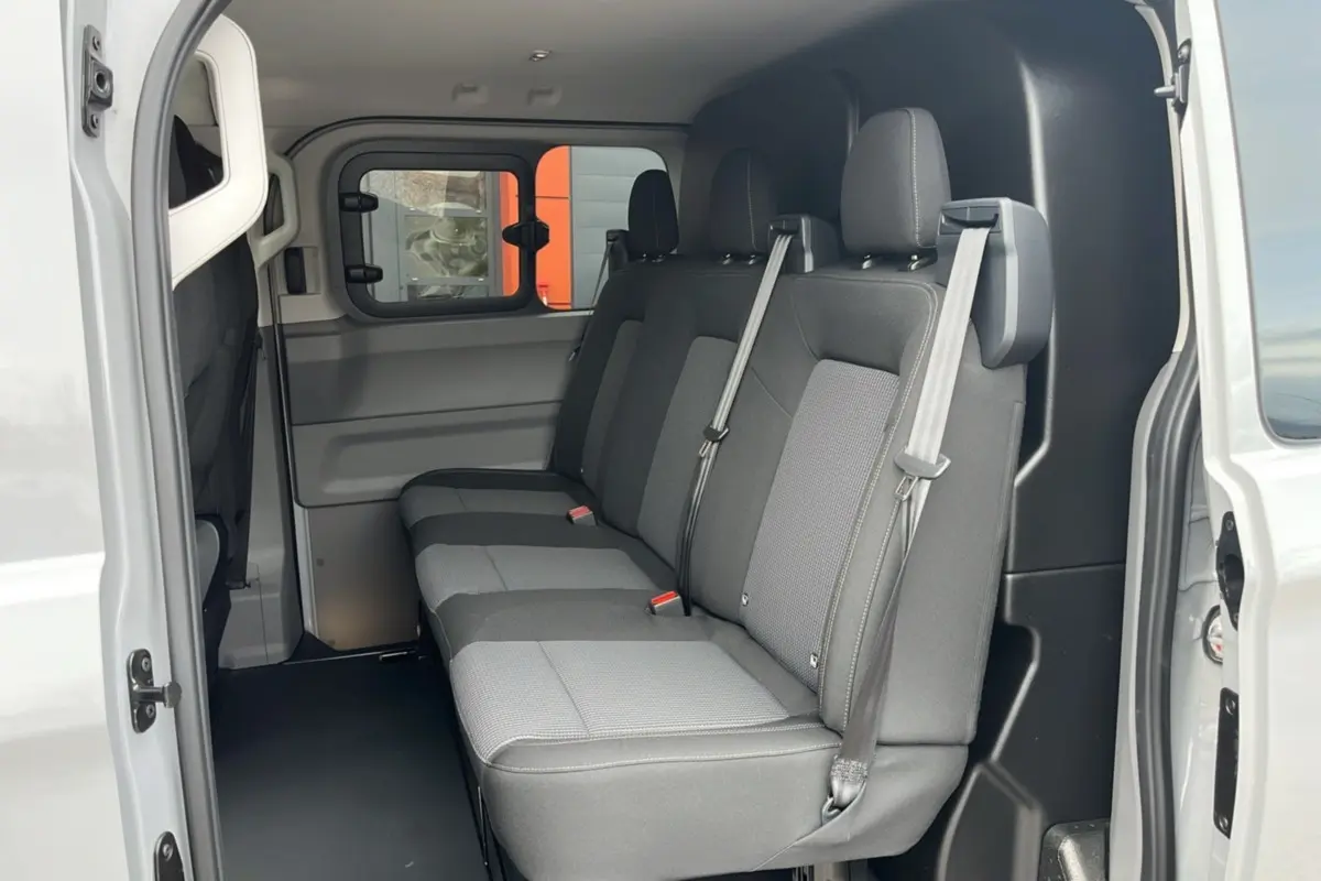 Vue intérieure côté droit du Volkswagen Transporter TDI 170 DSG ProCab L1, sièges arrière gris à trois places avec ceintures.