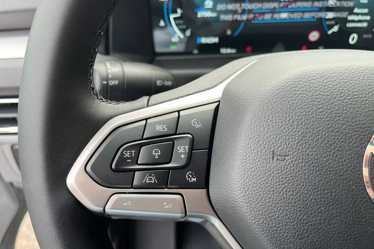 Gros plan sur le volant multifonctions noir du Volkswagen Transporter TDI 170 DSG 2026 avec commandes de régulateur adaptatif.