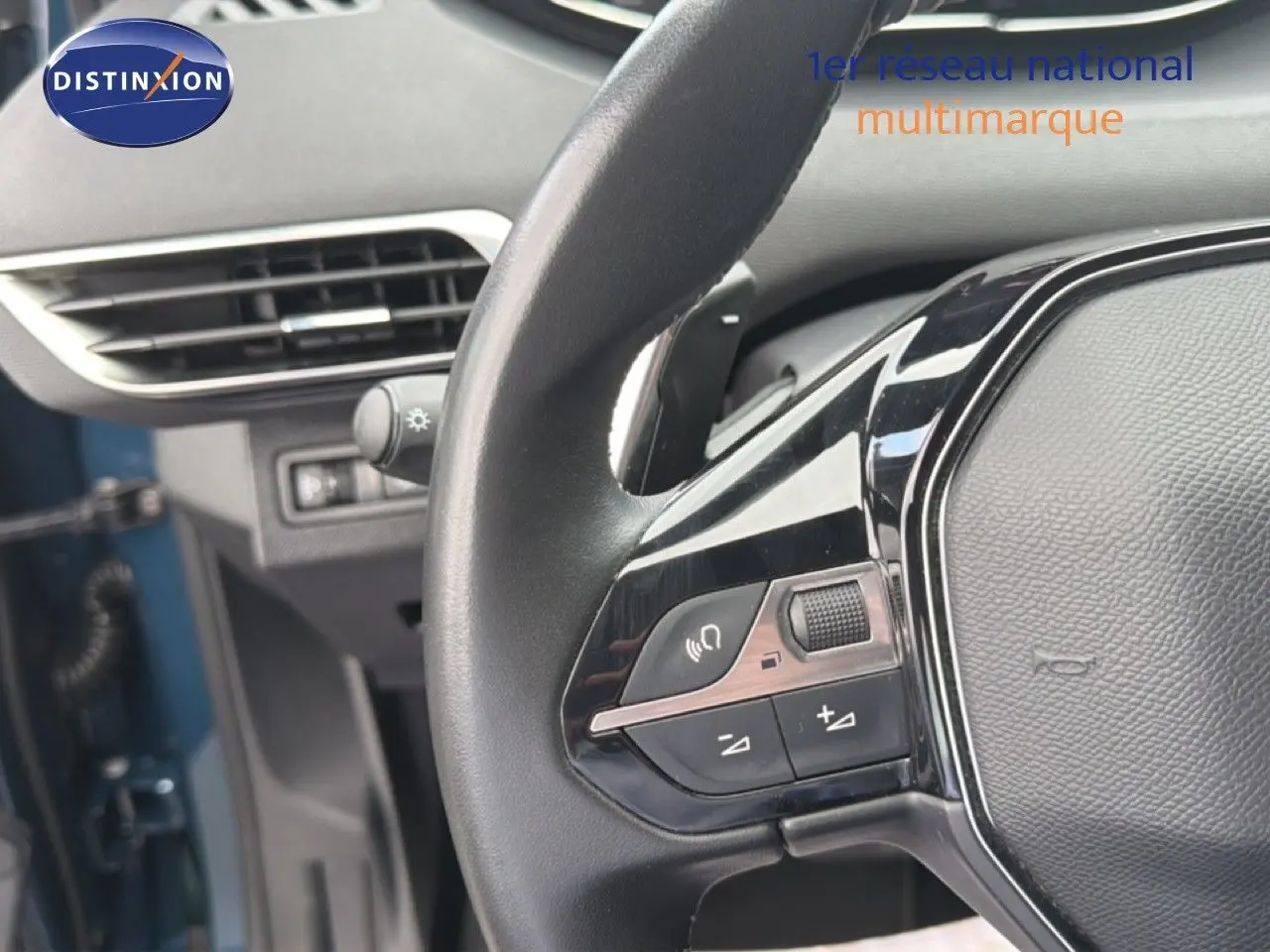 Gros plan sur le volant multifonction noir du Peugeot 5008 bleu Célèbes, avec commandes audio et téléphone visibles.