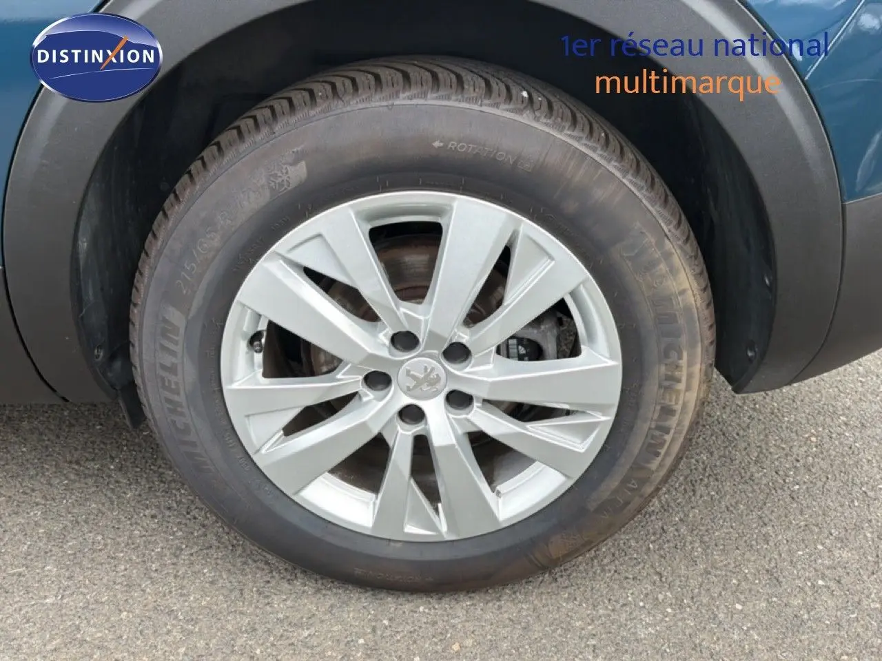 Gros plan sur la roue avant droite d’un Peugeot 5008 bleu Célèbes Métal avec jante alliage argentée.