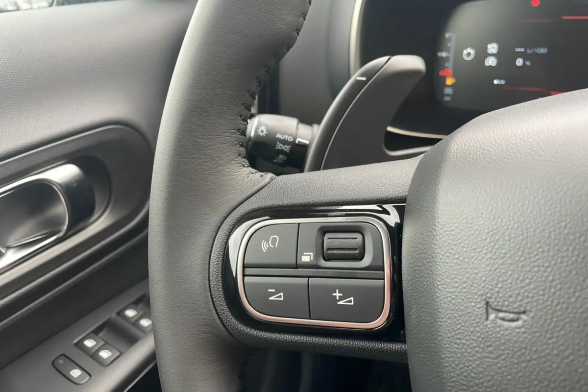 Gros plan sur les commandes au volant du Citroën C5 Aircross Hybrid 2025, intérieur noir avec détails chrome.