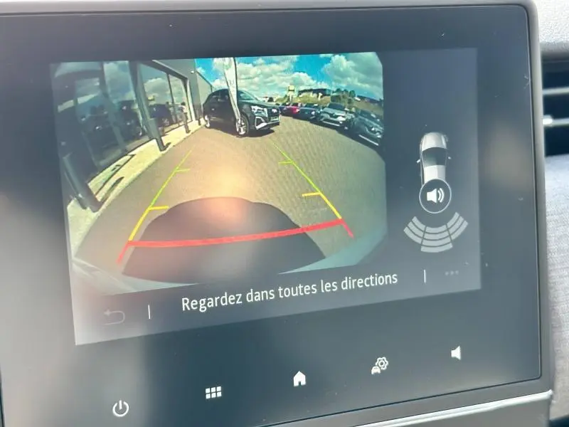 Image de la caméra de recul de la Renault Clio blanche montrant l'arrière avec lignes de guidage colorées.
