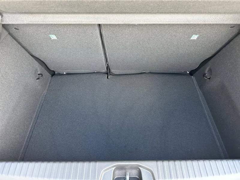 Vue plongeante sur le coffre spacieux et tapissé de tissu gris foncé de la Renault Clio Blanc Glacier 2025.