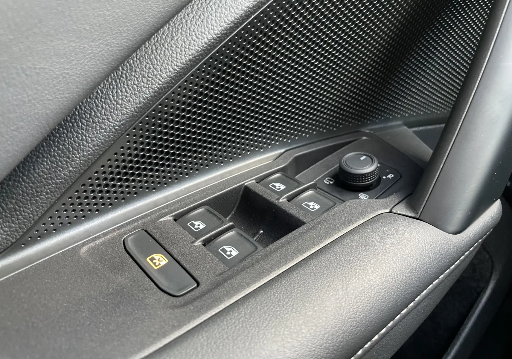 Gros plan sur les commandes des vitres et rétroviseurs côté conducteur du Volkswagen Tiguan 2024 en noir, avec finition texturée.