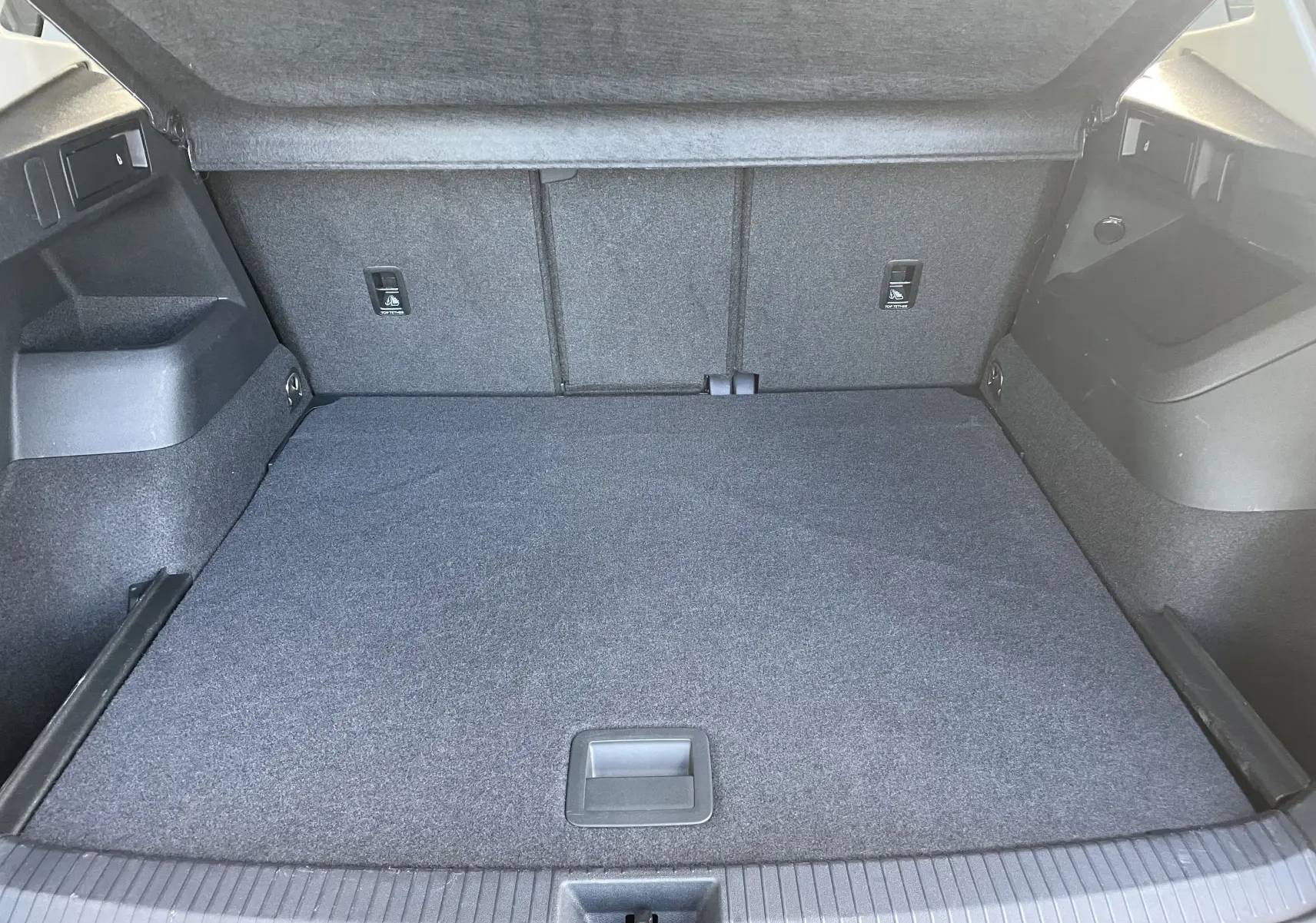 Coffre ouvert vu de l'arrière d'un Volkswagen Tiguan 2024, intérieur gris noir avec revêtement tissu.