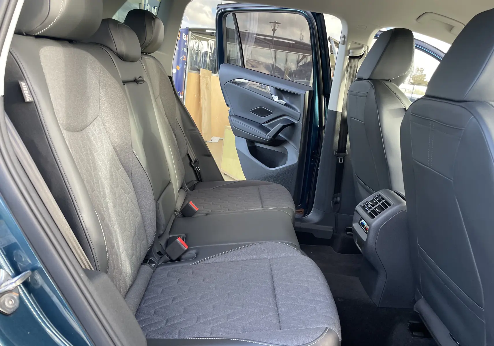 Vue intérieure arrière droite du Volkswagen Tiguan 2024 en Nightshade Blue, sièges gris noir et porte ouverte.