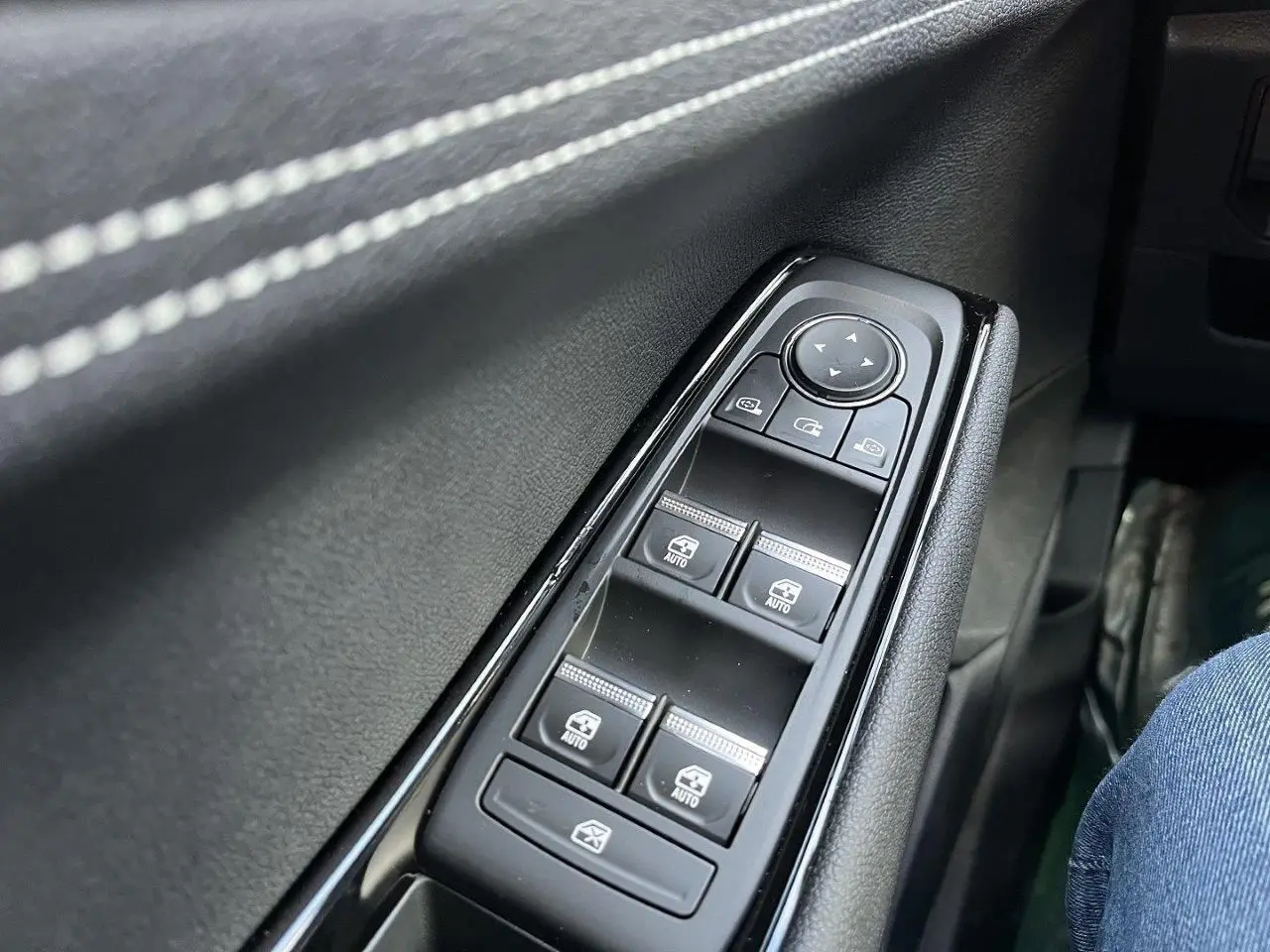 Gros plan sur les commandes des vitres électriques côté gauche d’un Renault Austral gris schiste, intérieur noir.