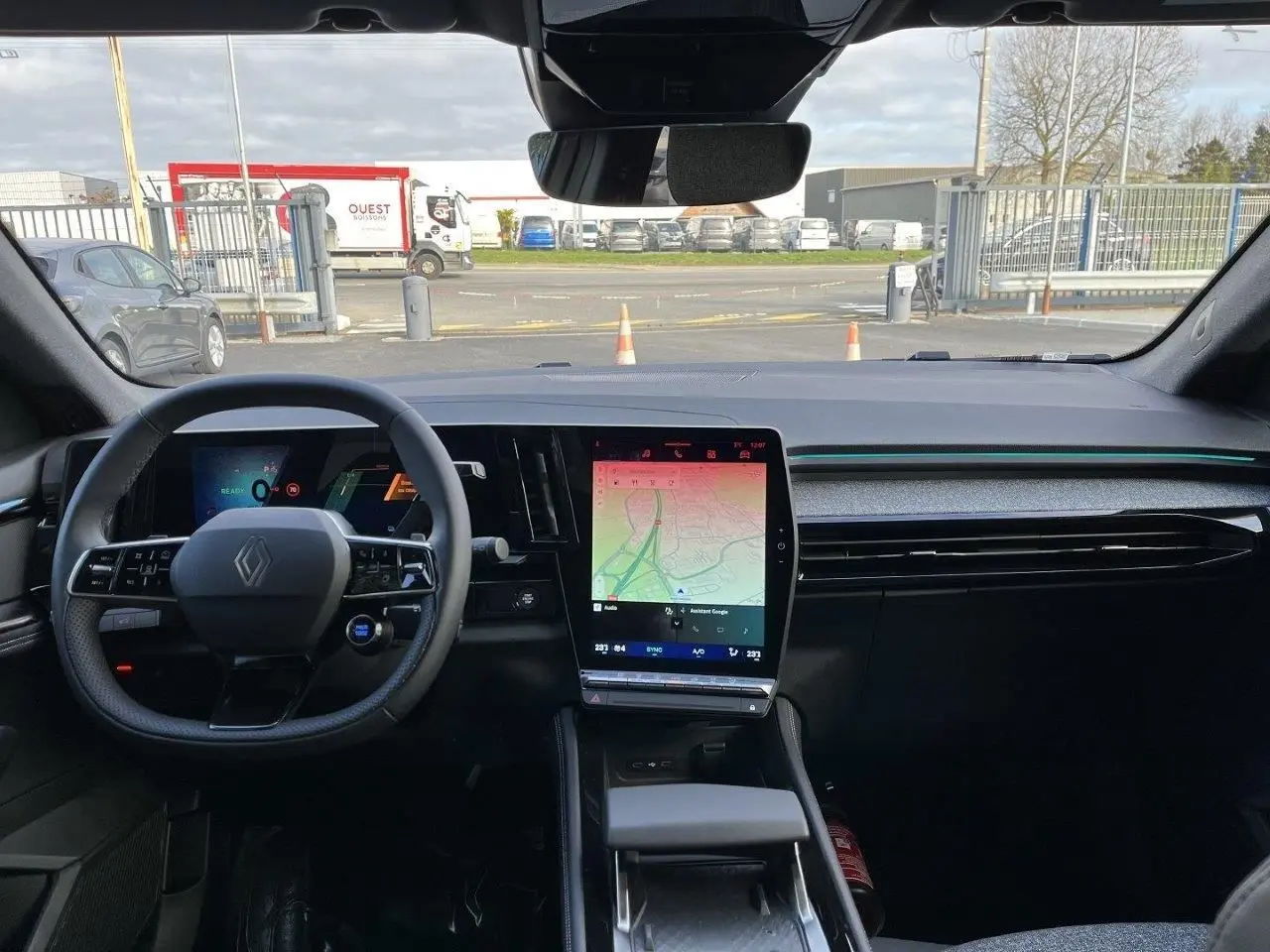 Vue intérieure avant du Renault Austral Ph.2 gris schiste, mettant en valeur le tableau de bord digital et l’écran central tactile vertical.