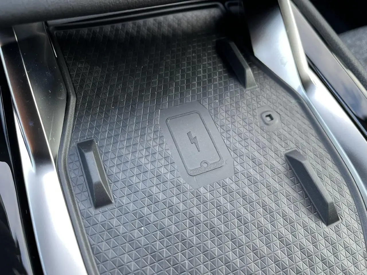 Gros plan sur le chargeur à induction noir au centre de la console intérieure du Renault Austral gris schiste.