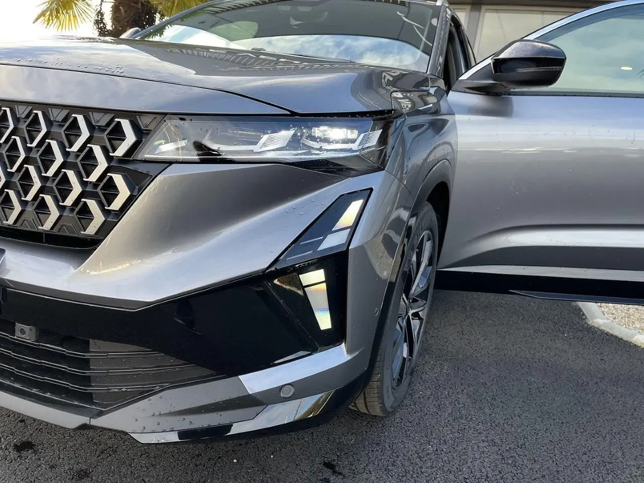 Vue avant droite du Renault Austral Ph.2 gris schiste, avec calandre hexagonale et porte ouverte côté passager.