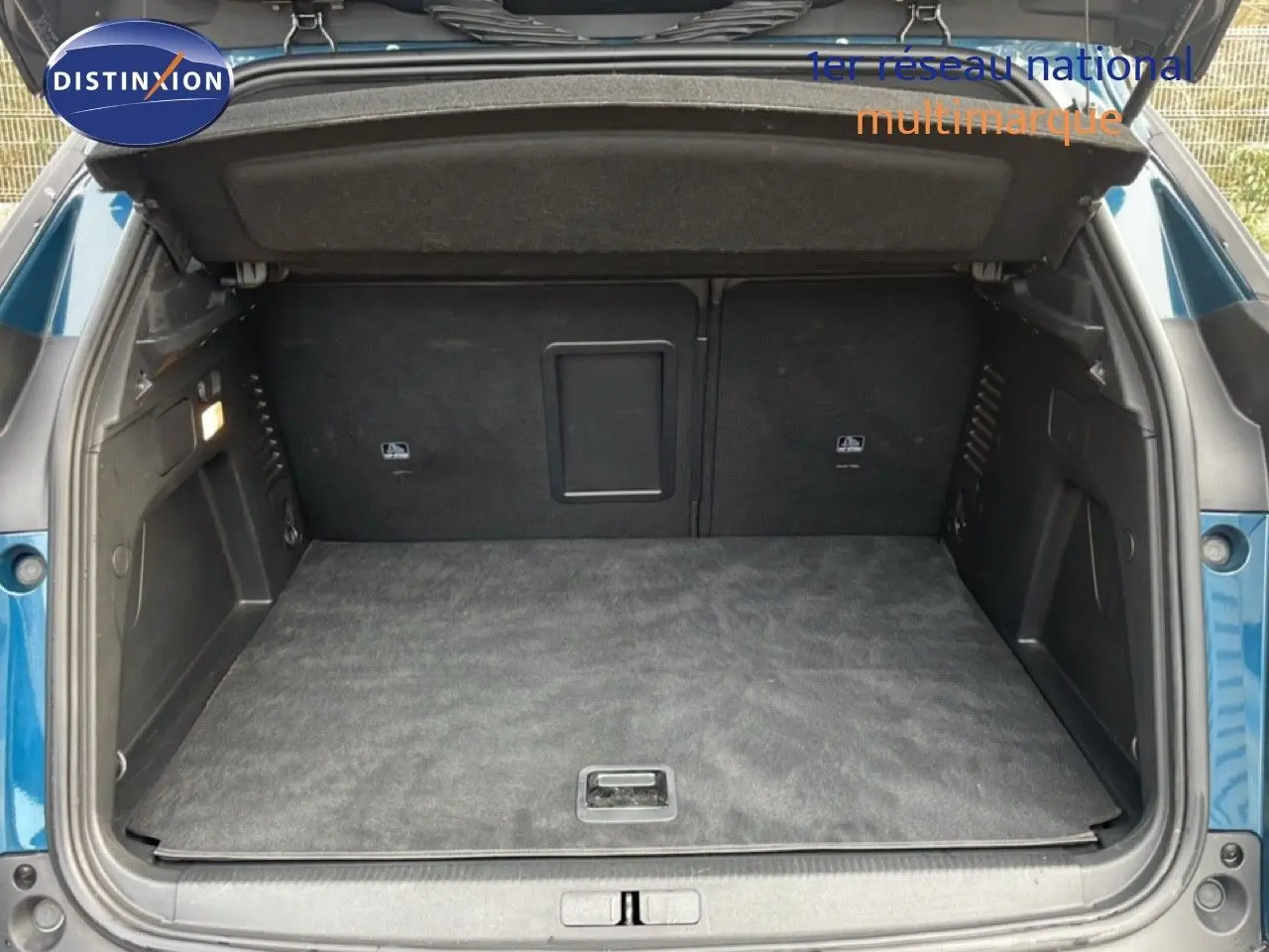 Coffre ouvert du Peugeot 3008 hybride bleu Célèbes Métal, vue arrière montrant un espace de chargement spacieux et propre.