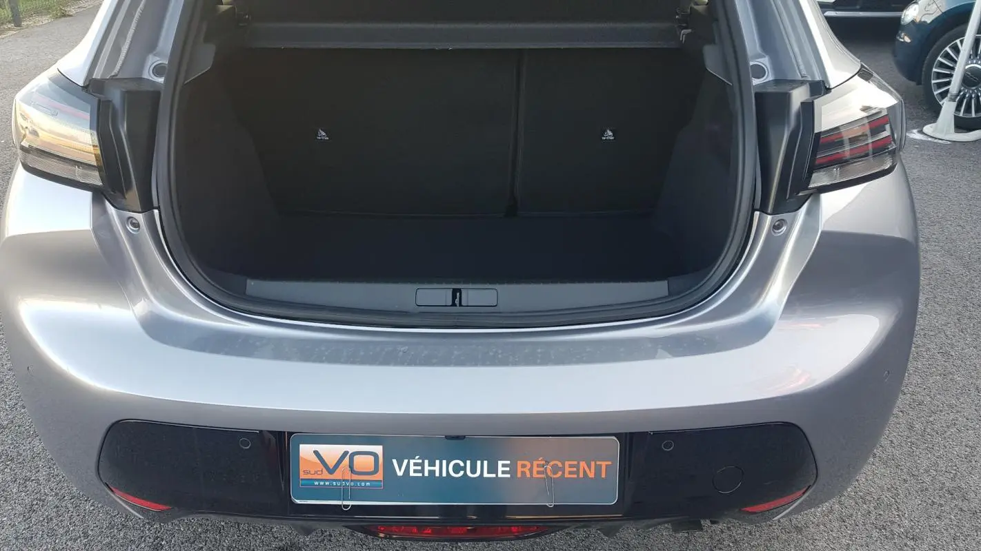 Vue arrière ouverte sur le coffre d’une Peugeot 208 Hybrid 110 gris, avec feux arrière LED et plaque VÉHICULE RÉCENT.