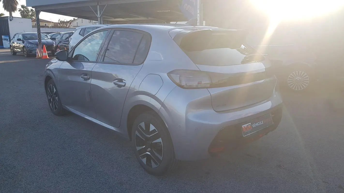 Vue 3/4 arrière droite d'une Peugeot 208 Hybrid 110 gris métallisé avec jantes alliage et antenne requin.