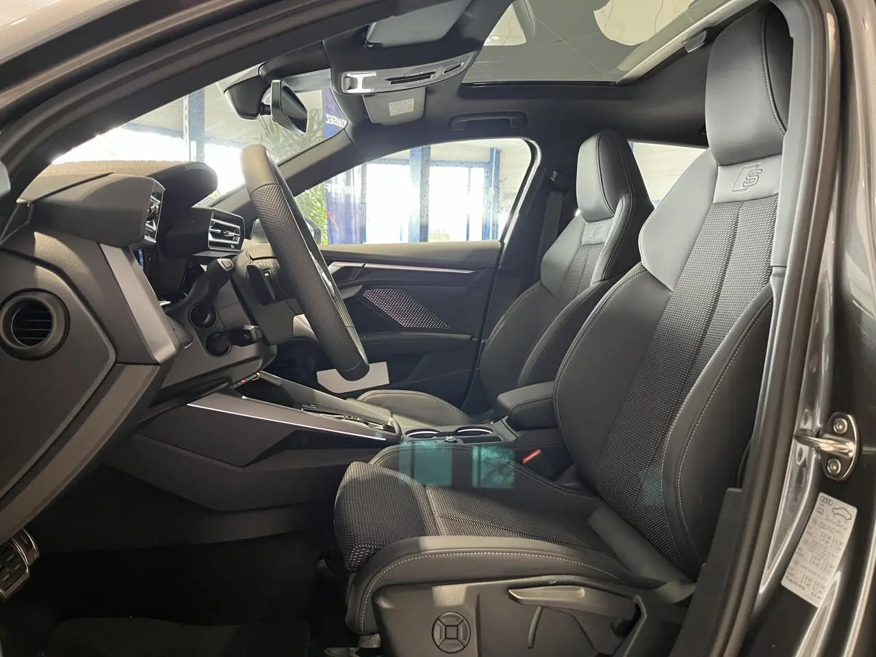 Vue intérieure côté conducteur de l'Audi A3 Sportback gris, sièges sport S line en cuir avec logo S embossé.